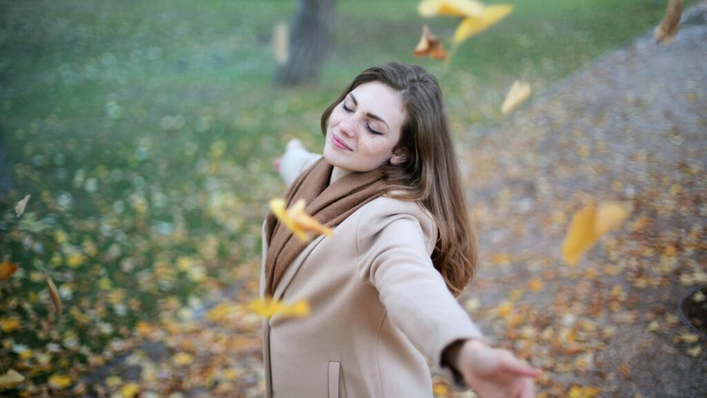 A woman in a coat enjoying an autumn day.