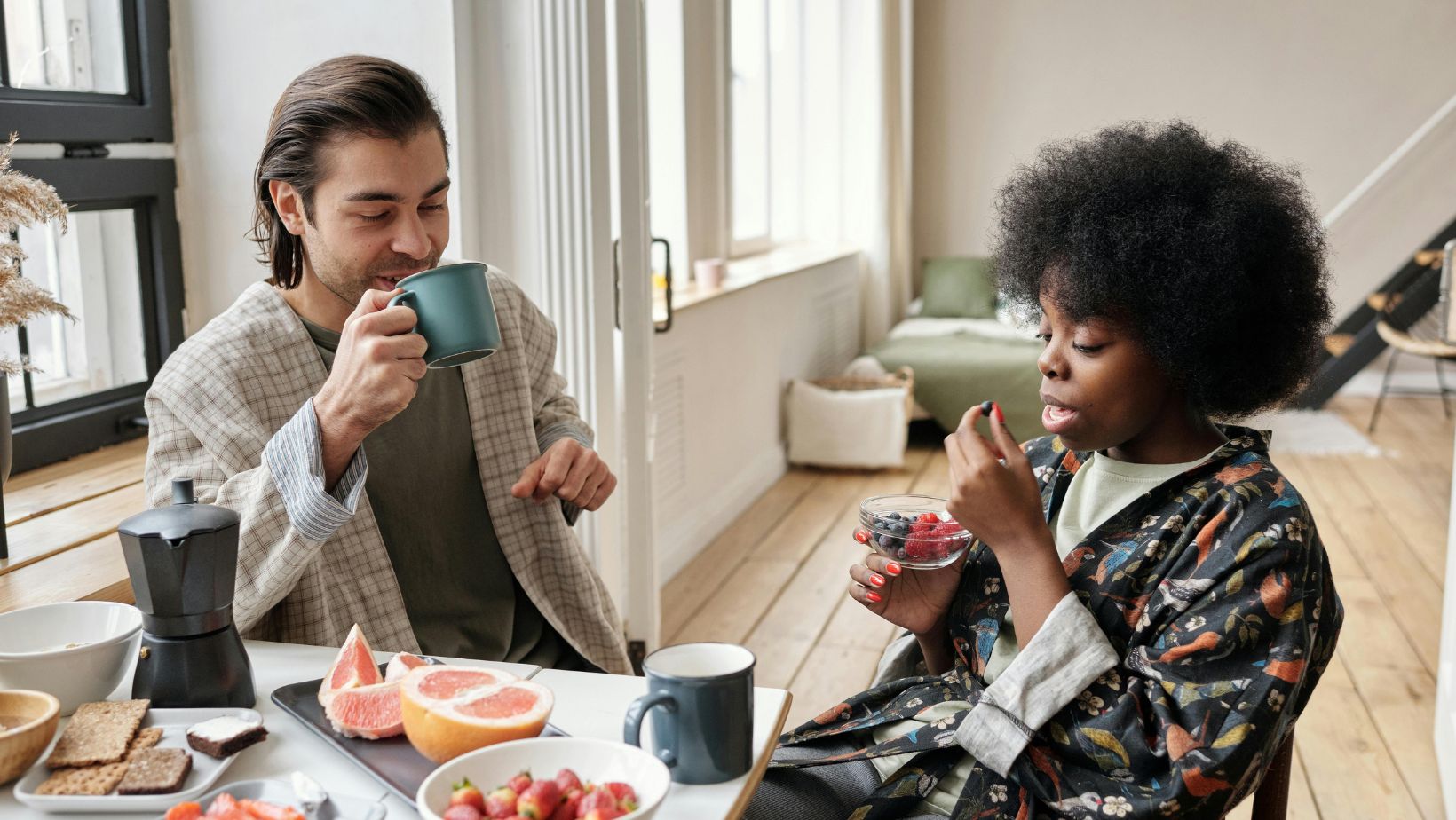 Two people sitting at a table eating fruit.